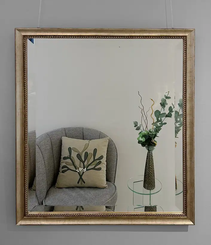 Facettenschliff-Spiegel in Goldrahmen, Stuhl und Tisch sichtbar darin