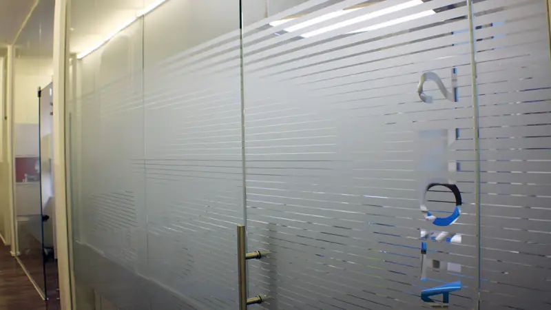 Glastrennwandsystem mit Drehtüre und gestreiften Sandstrahlmuster