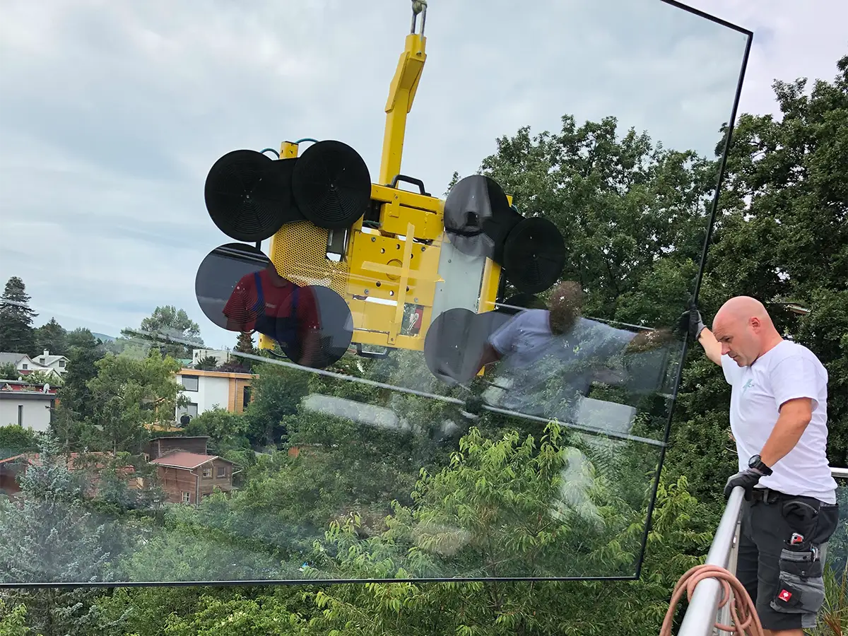 Mitarbeiter hilft bei Platzierung des Isolierglases, welches mit Kran und Glassauger gehoben wird