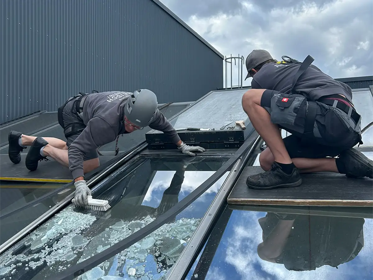 Reparatur eines Glasdachs mit Isolierglas, Entfernung der Einscheibensicherheitsglas-Splitter, Mitarbeiter mit Schutzausrüstung
