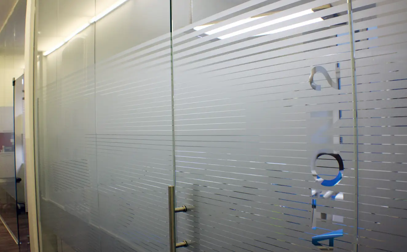 Glastrennwandsystem mit Drehtüre und gestreiften Sandstrahlmuster